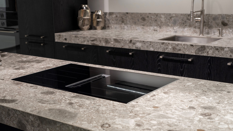 A black induction cooktop with built-in ventilation system on stone