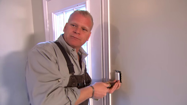 Mike Holmes standing next to a white door.