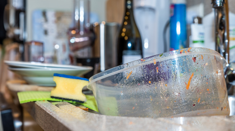 A dirty food container in a kitchen sink