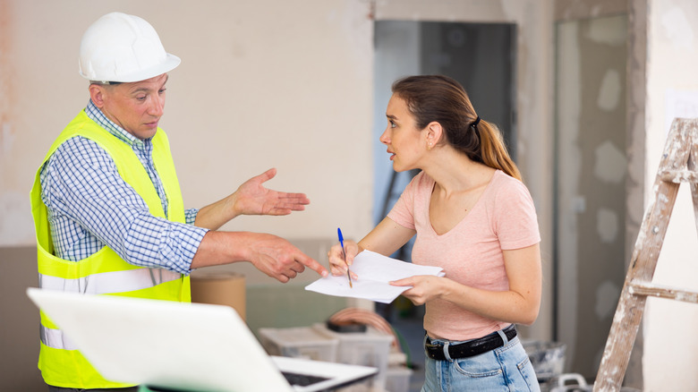 An annoyed homeowner disputing details on a piece of paper with a contractor