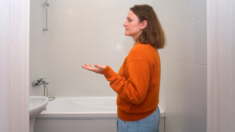 A woman looking annoyed as she inspects her bathroom