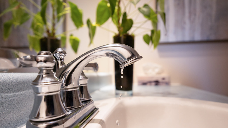 A bathroom faucet slowly dripping water