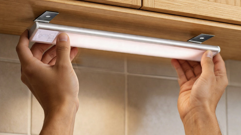 A person installing one of Energetic's Rechargeable 12-inch LED Wireless Undercabinet Lights