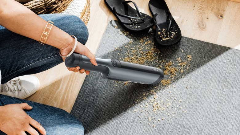 A person using Shark's WandVac Power Pet Cordless Hand Vacuum