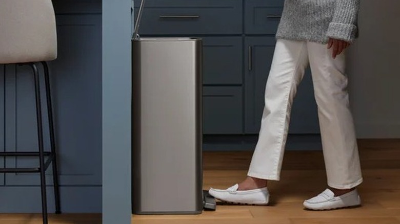 Woman stepping on the pedal of a trash can in a kitchen