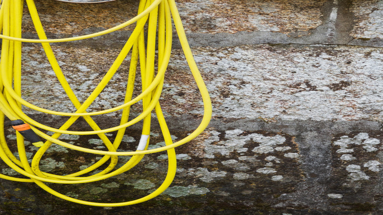 A water hose hanging from an old wheel rim.