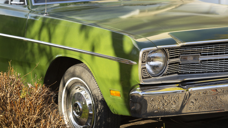 The front end of an old green car.