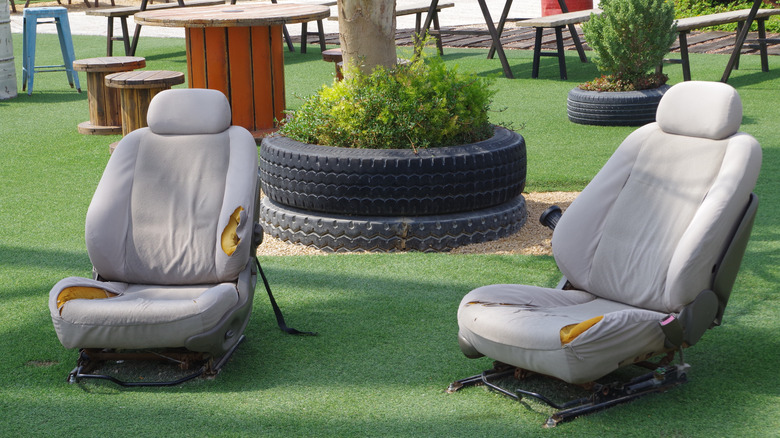 Two old car chairs in a garden.