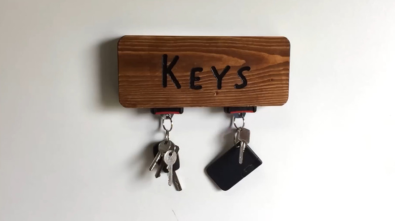 A seat belt buckle key holder on a wooden block.