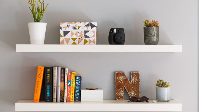Books displayed on floating shelf with other decor items and plants