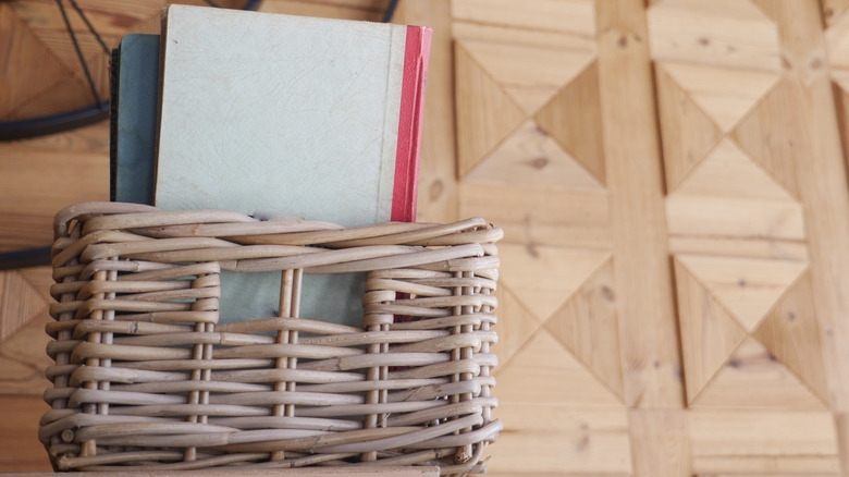 Books in a wicker basket against a wooden wall