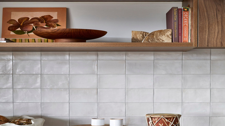 Cookbooks in kitchen on shelf next to stone pieces and bowl