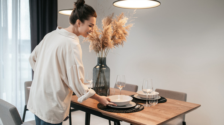 A person setting the table in a dining room