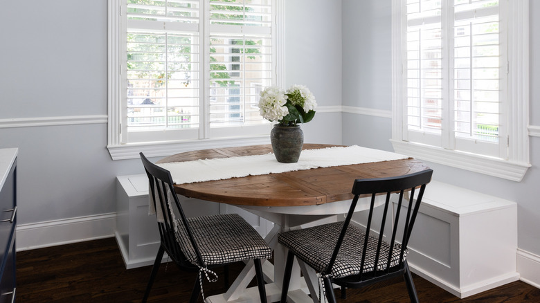 A dining room with stark white window trims, white storage, a white table runner, and whiter countertops