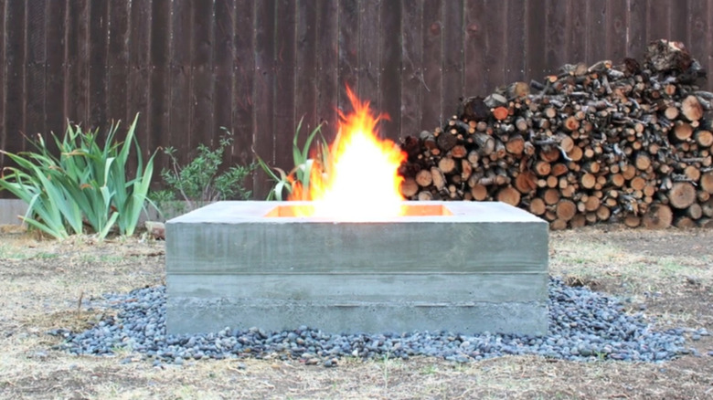 A concrete fire pit with logs in the background