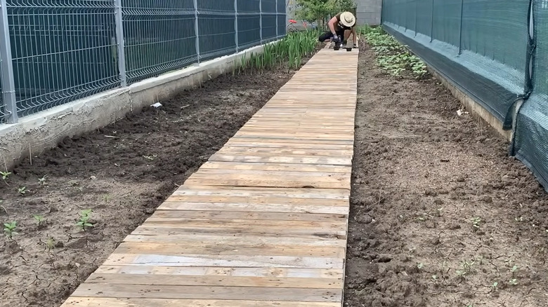Person building a raised pallet wood walkway