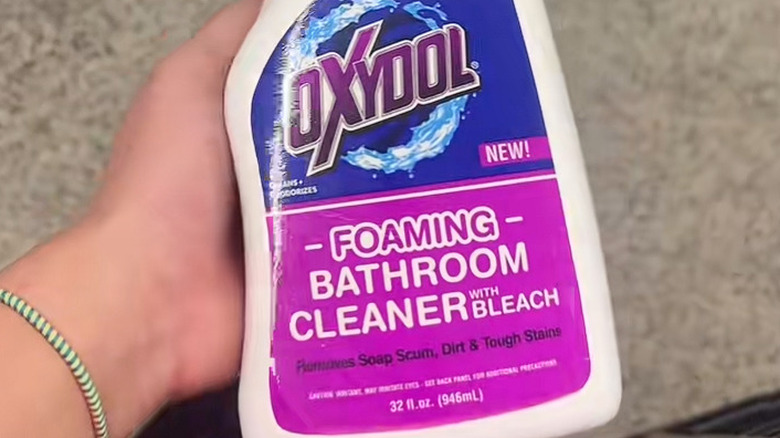 A woman holding the Oxydol brand foaming bathroom cleaner.