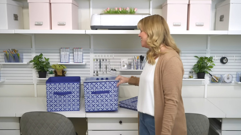 A woman placing a plastic bin inside a storage cube
