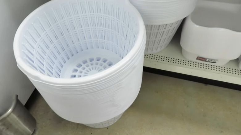 A stack of white laundry baskets in the aisle of a store