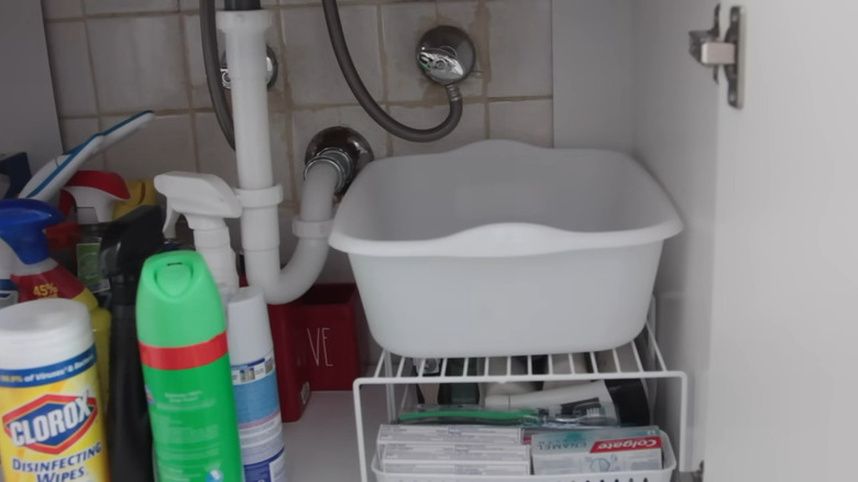 A white bin and cleaning products under a sink