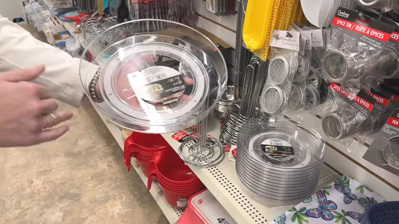 A person holding a clear lazy susan in a store aisle