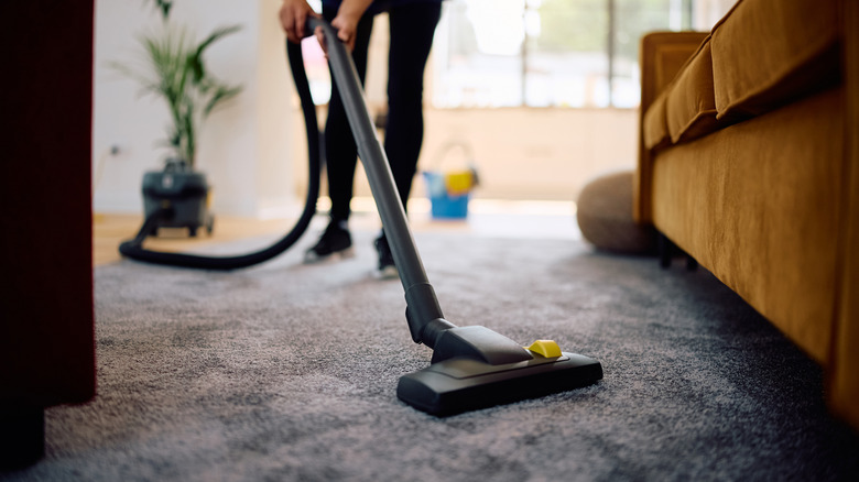 Homeowner vacuuming grey carpet