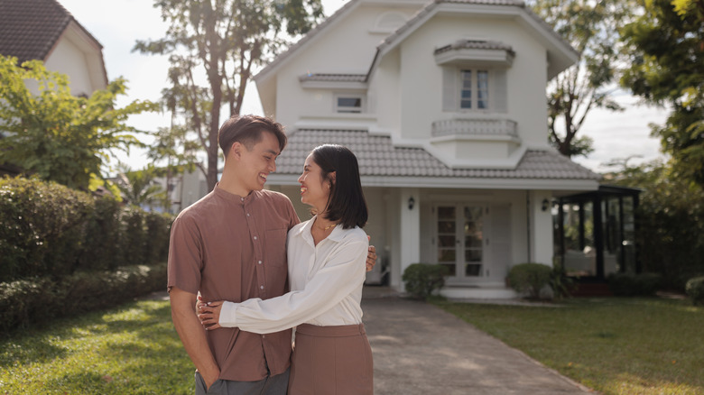 young couple standing in front of their first home