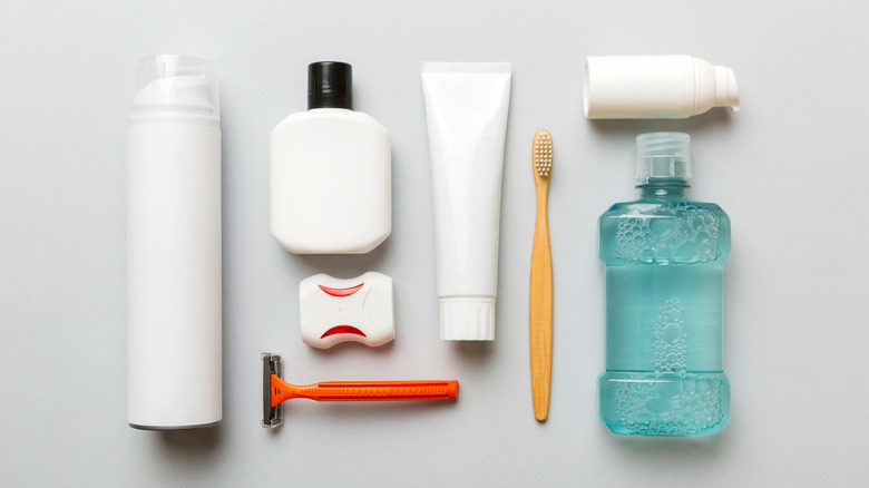 Personal care items like an orange razor and toothbrush laying on a white surface.