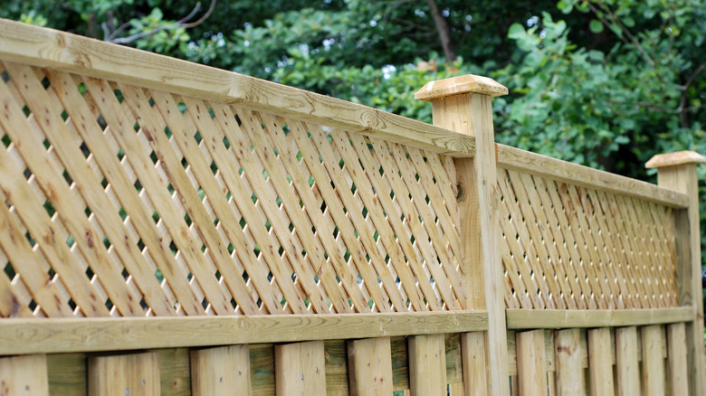 A wood fence with a lattice trim