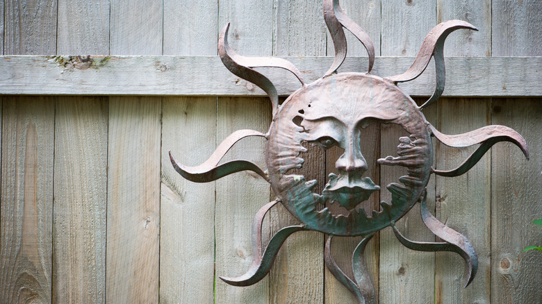 A metal sun decal on a wood fence