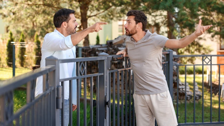 Two men fighting over a fence