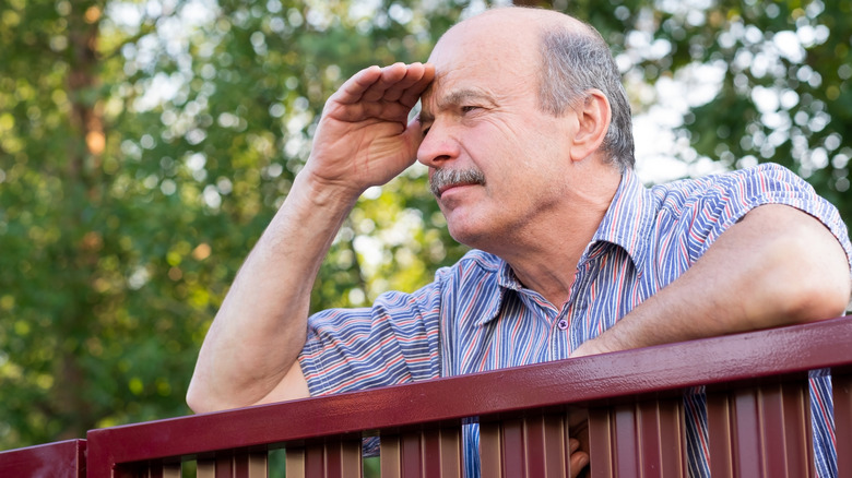 Older man snooping over top of fence