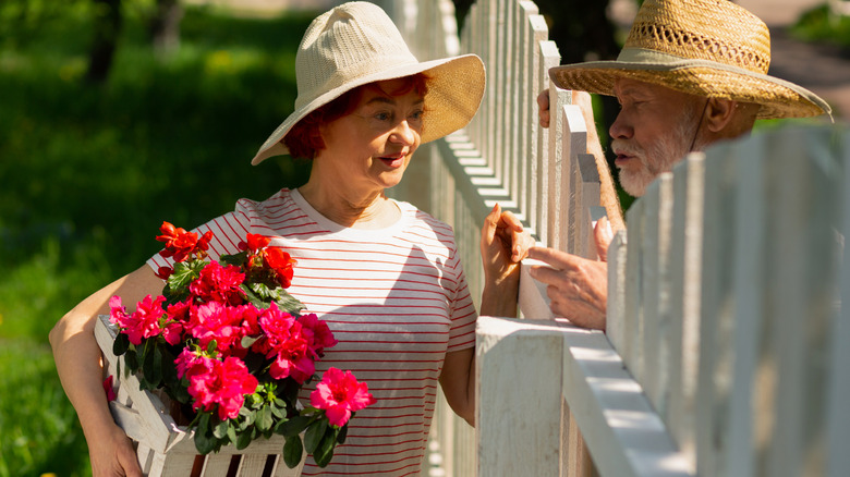 Retired friendly neighbors standing near fence