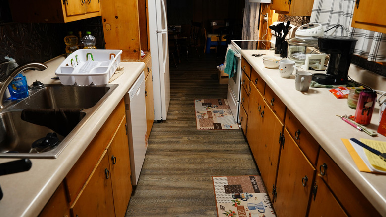 A messy galley kitchen with cluttered worktops