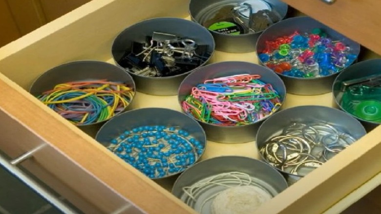 Tuna cans act as separate drawer organizers for office supplies.
