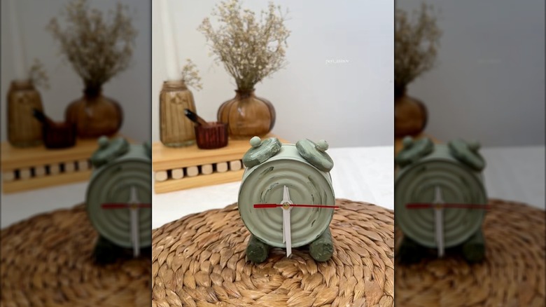 A tuna can with wine cork feet are painted and converted into a clock.