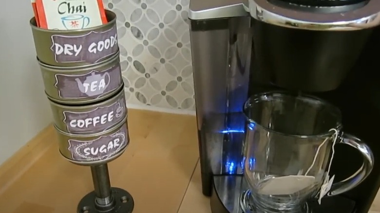 Four stacked cans attached at a pivot point store small items.