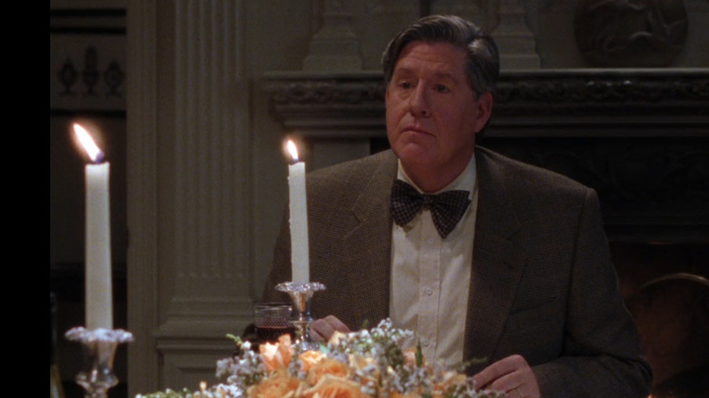 A man sitting at a table and two candlesticks burning in front of him