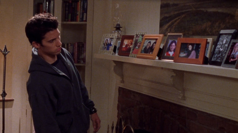 man looking at a mantle of photo frames