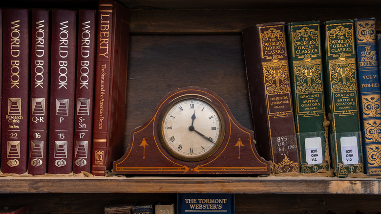 A wooden clock between books