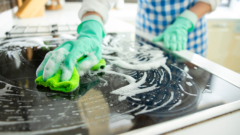 Close-up of a person cleaning a glass stovetop