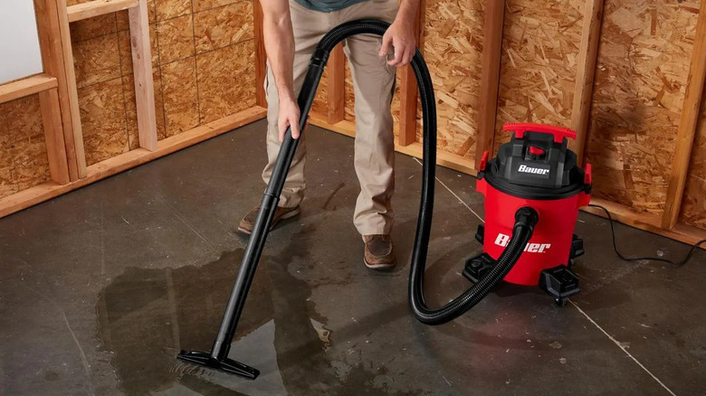 A person clearing up a water puddle with Bauer's 6-Gallon, 4 Peak HP Wet/Dry Vacuum