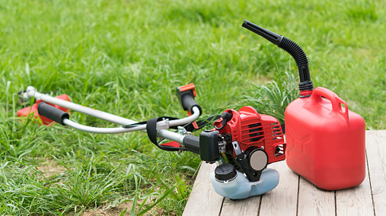 A gas-powered lawn tool next to a jerry can