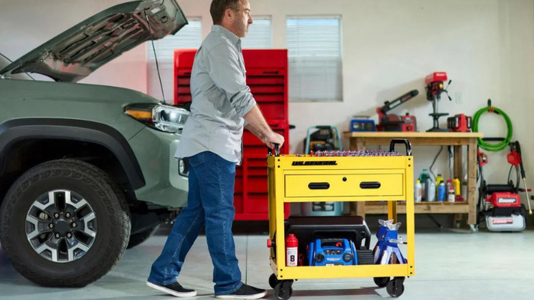 A man pushing U.S. General's 30 in. 1-Drawer Service Cart in a garage