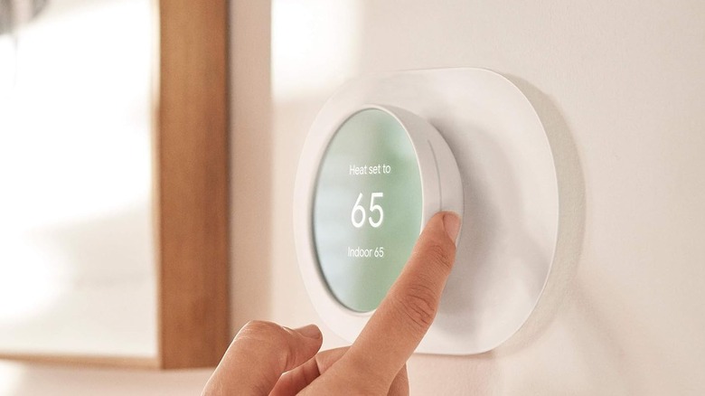 Hand changing the temperature on a white thermostat