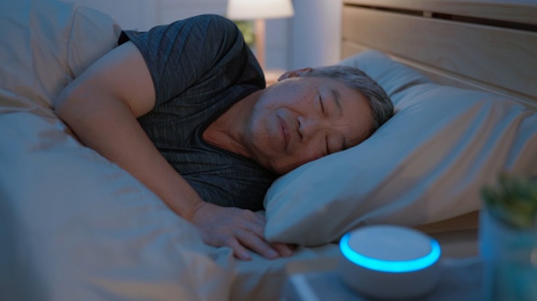 Man sleeping with a white noise machine on the nightstand