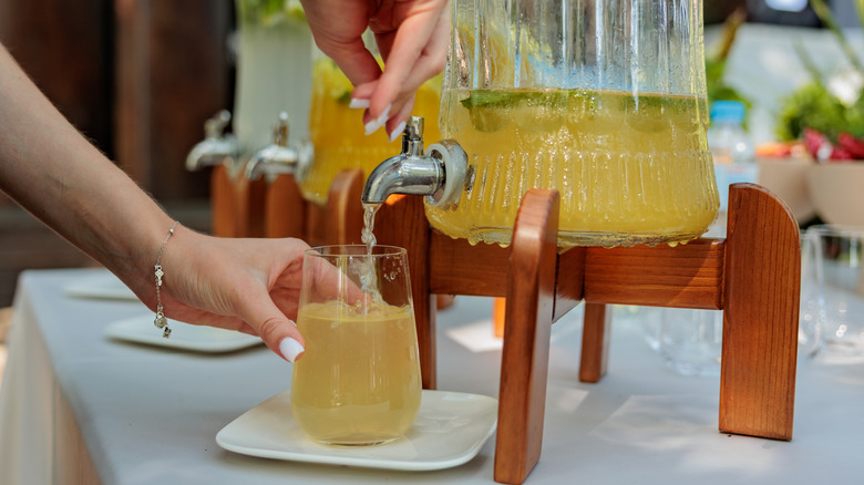 A person pours themselves a drink from a dispenser