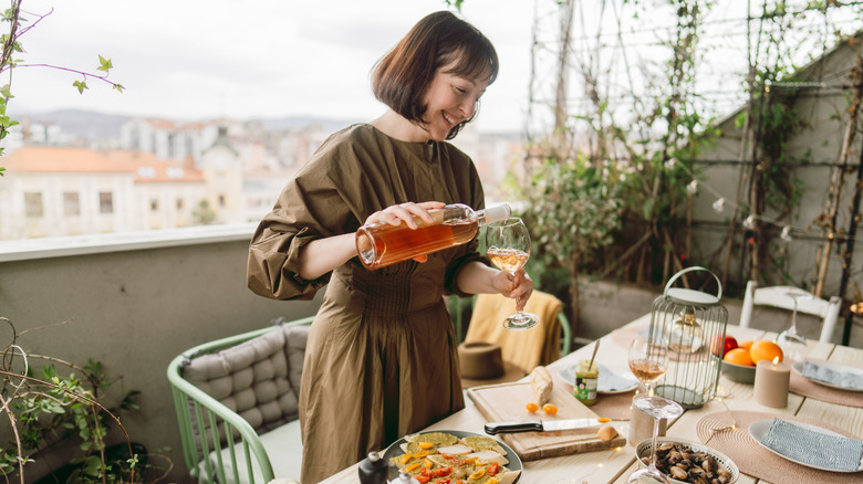 A woman pours drinks as she hosts a dinner party on her patio