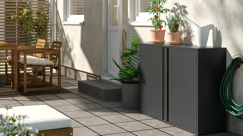 The SUNDSÖ outdoor/indoor cabinet (in black) on a garden patio