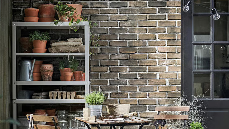 The 6-tier shelving unit from the KOLBJÖRN collection in the corner of an outdoor courtyard